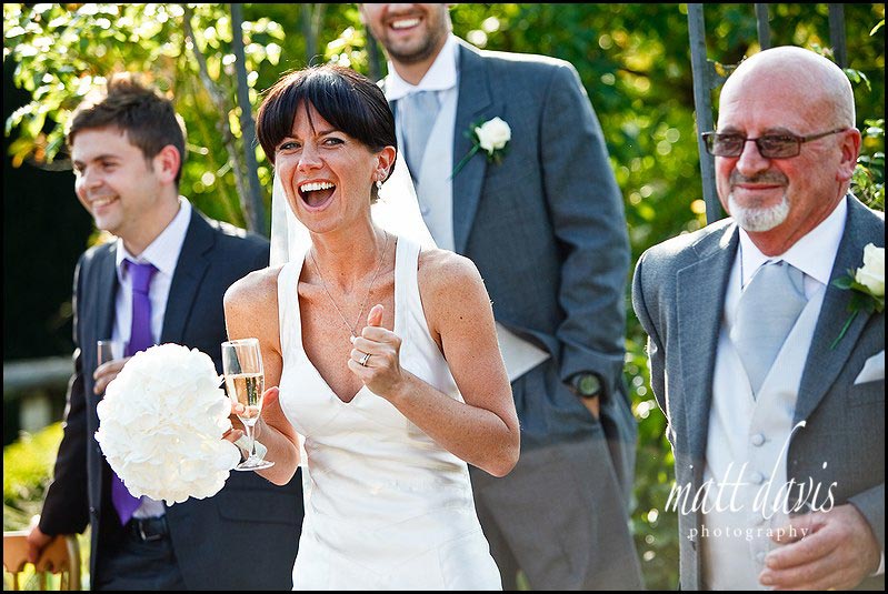bride laughing during outdoor wedding speeches in Birtsmorton Court white garden