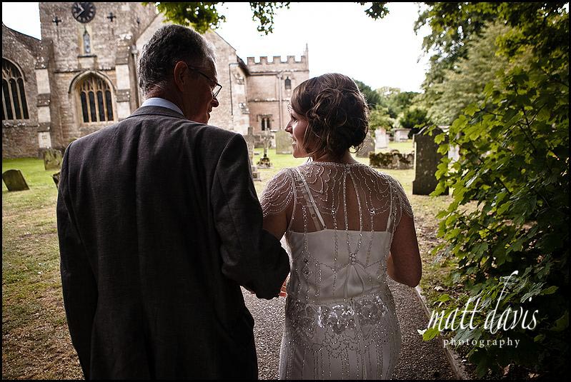 Father and bride walking into Crudwell church grounds