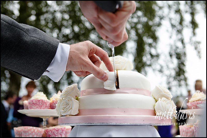 Vintage wedding cake cut by bride and groom