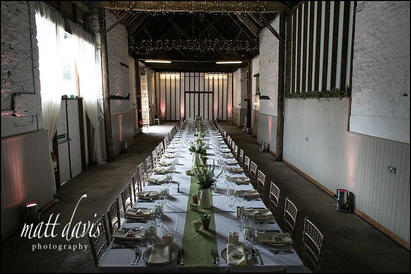 Long table layout for wedding in Friars Court barn with flowers and bird cages