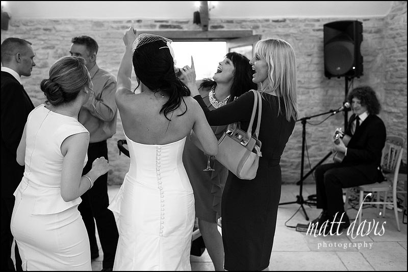 Bride and wedding guests dancing in the reception room at Kingscote Barn