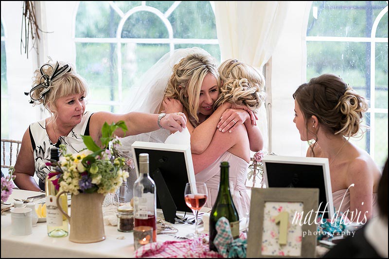 bridesmaid having a hug from the bride after crying as she opens her wedding gift