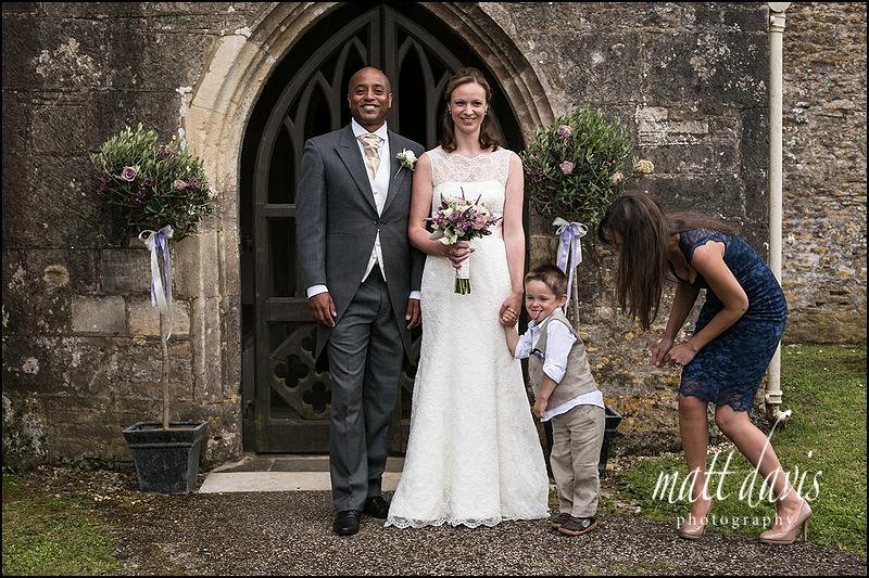 Couple pose for a photo in the doorway of Kingscote Church, Gloucestershire