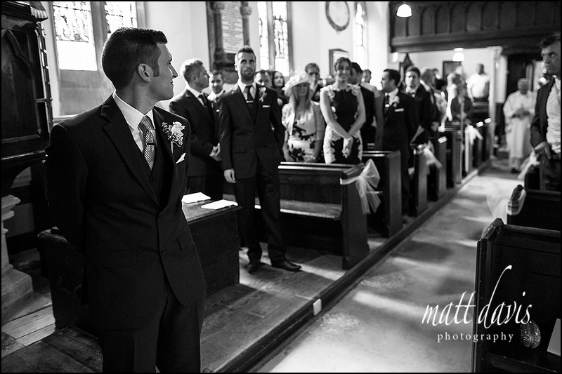 black and white photography inside Kingscote church showing waiting groom