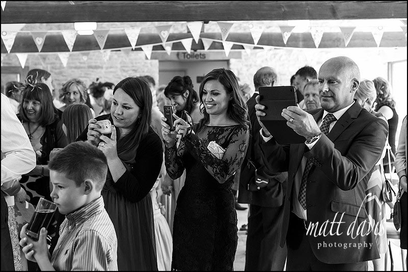 Wedding guests photographing the married couple cutting the cake
